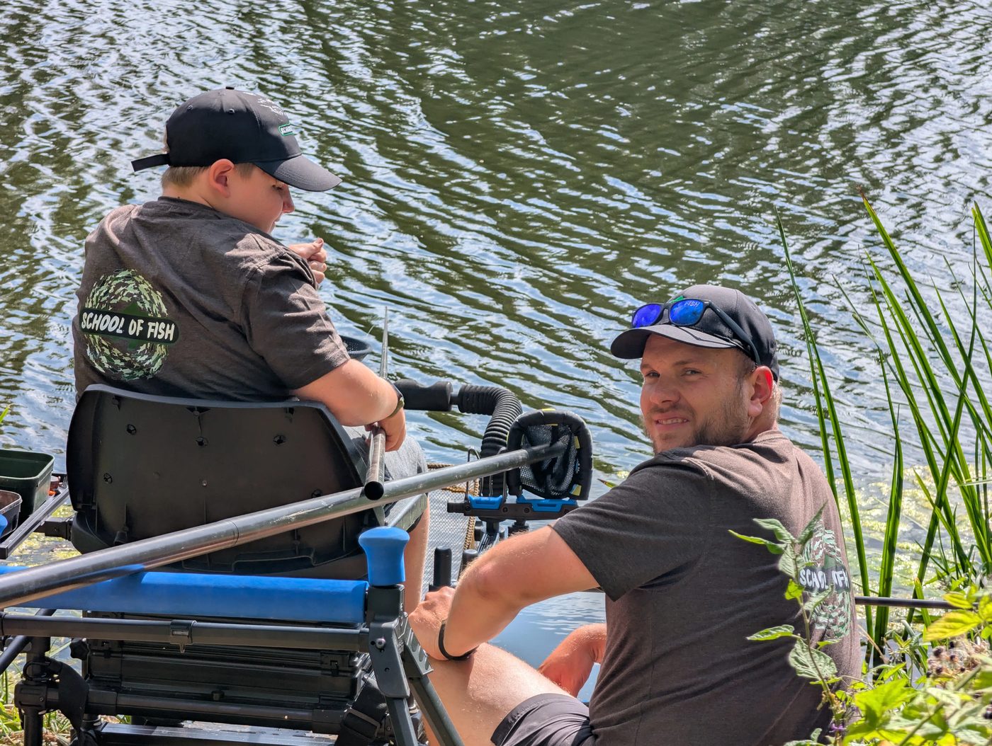 A School Of Fish coach smiling at the camera beside a young angler on the box