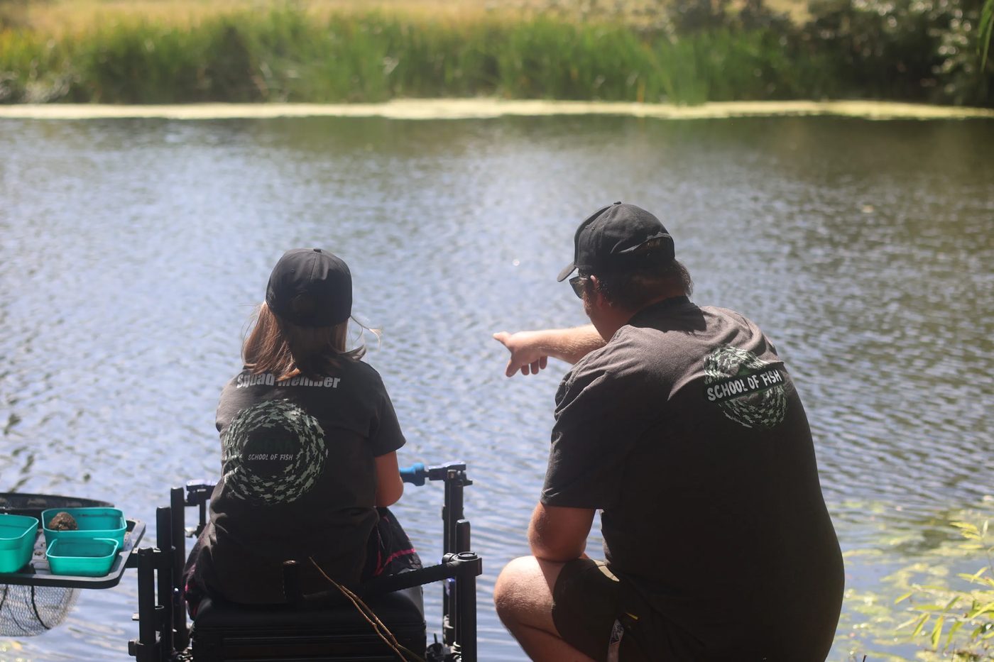 A coach pointing out a spot on the water to a young angler