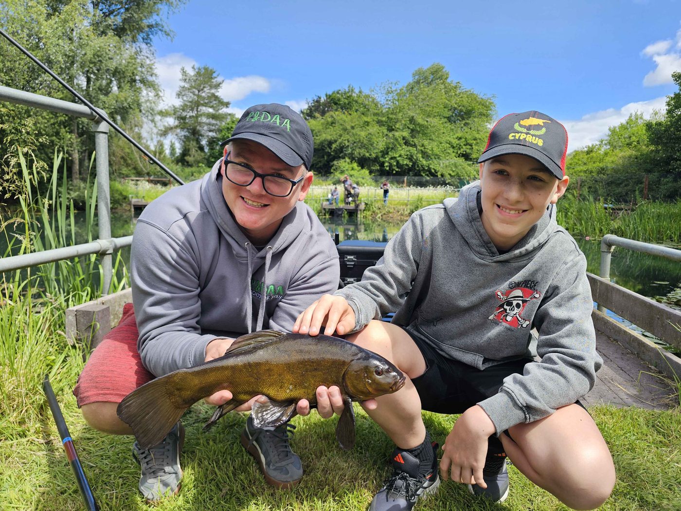 A coach and young angler holding a tench at the bank
