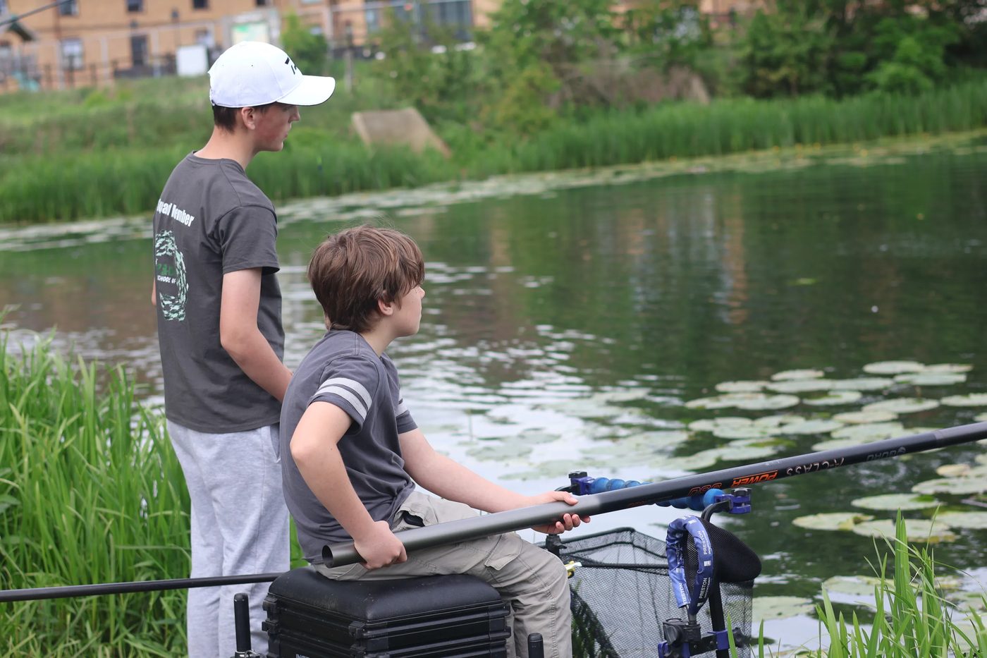 Two young anglers fishing a lily-fringed pond