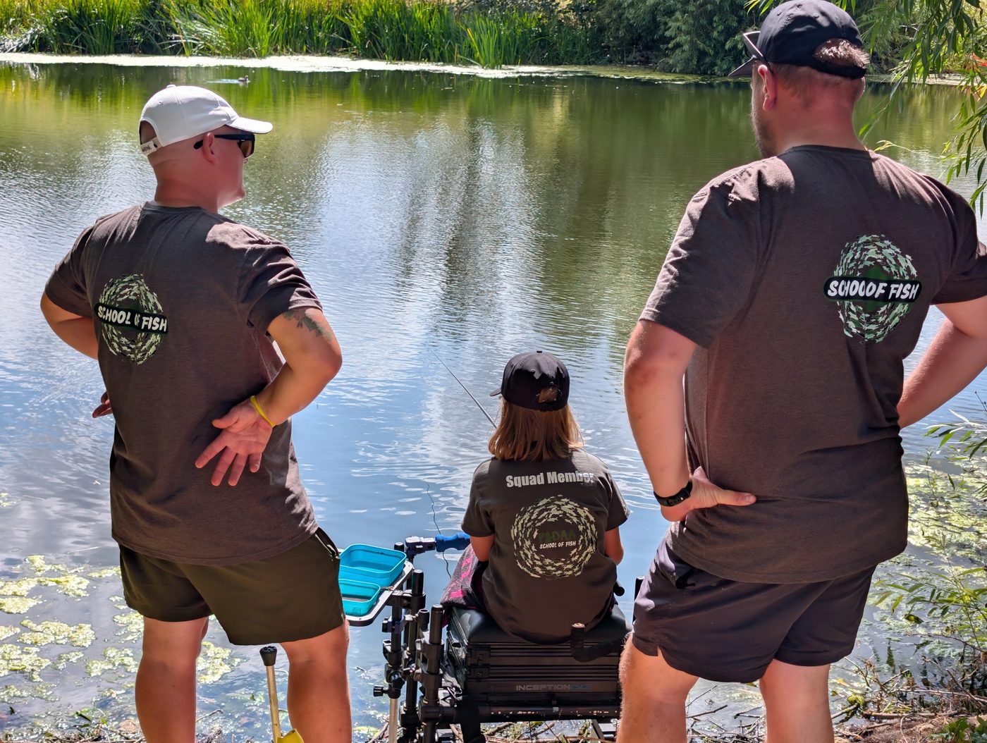 Two School Of Fish coaches standing either side of a Squad member fishing the pool