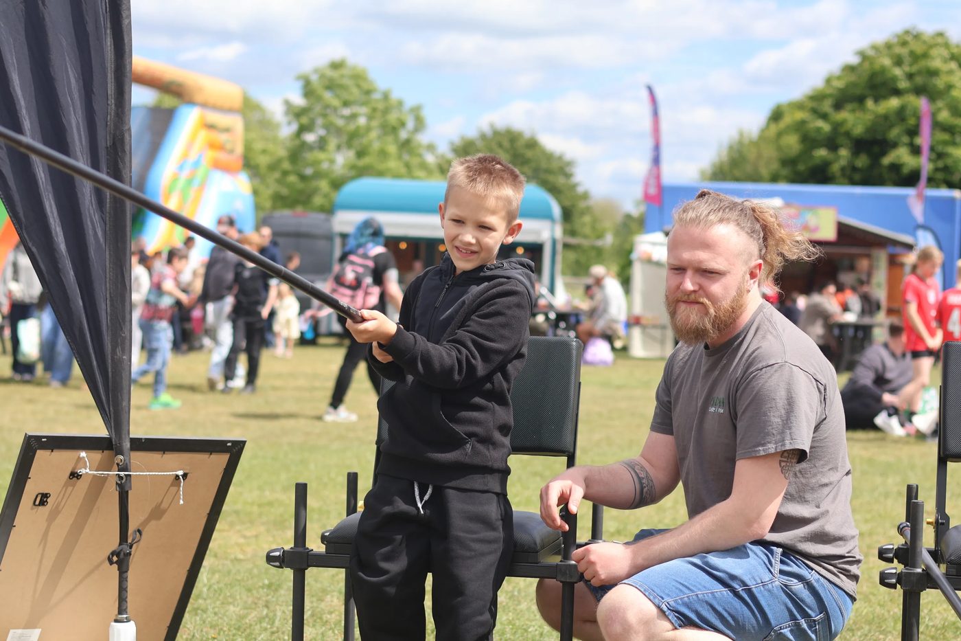 A young angler trying a rod with a coach at an event